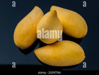 Ripe yellow barracuda mango fruit (Nam Dok Mai) on black table background. Tropical healthy fruit background, Selective focus. Stock Photo