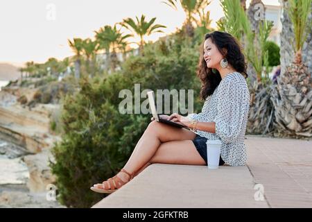 Young Asian woman works with her laptop remotely outdoors Stock Photo