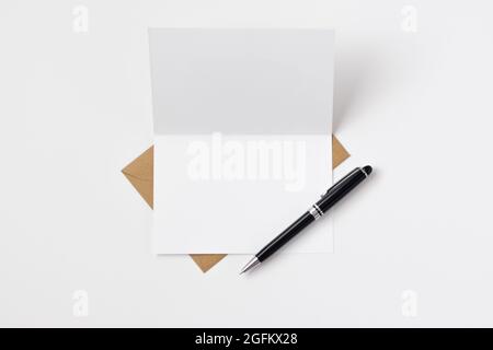 Open blank card with brown envelope and black and silver pen Stock Photo