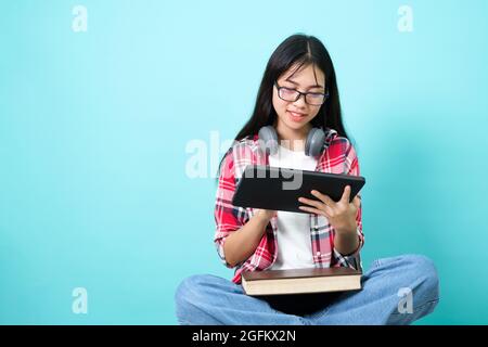 Happy student. Cheerful Asian Girl Smiling To Camera Standing With Backpack In Studio Over Blue Background. Back to school concept. Stock Photo