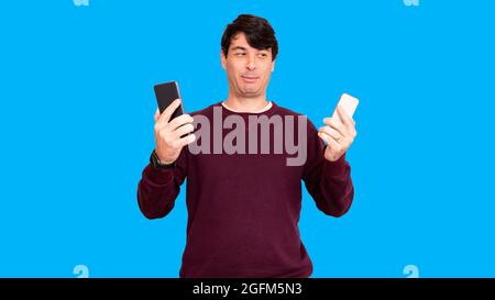 Man in wool blouse. Holding two smartphones in hands. Stock Photo