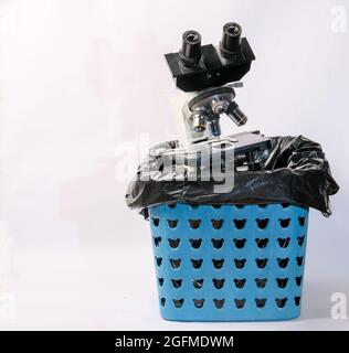 Photo of  compound light microscope in a plastic trash bin. Stock Photo