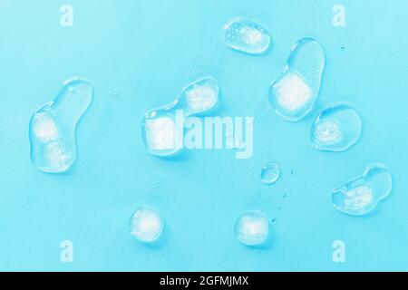 Melting ice cubes scattered on a blue background, top view. Texture. Stock Photo