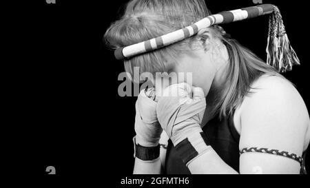 Muay Thai fighter girl preparing for battle. Black and white portrait against black background. Copyspace. Stock Photo