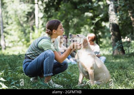 Side view of girl pouting lips while looking at retriever in park Stock Photo