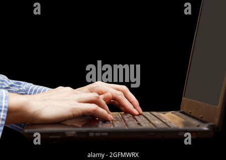 Human hand on the keyboard of notebook on the darkness. Work on the computer, writing a blog, search on the internet, communication in social networks Stock Photo
