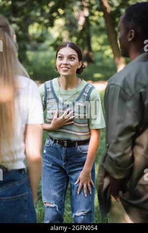 Happy teen girl talking to interracial friends outdoors Stock Photo