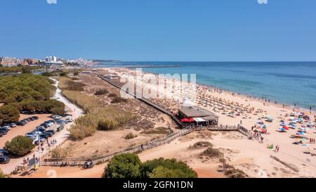 Aerial view of the luxury Falesia beach in Vilamoura. With sunbathing tourists on sun beds. Marina port with yachts, in the background. Stock Photo