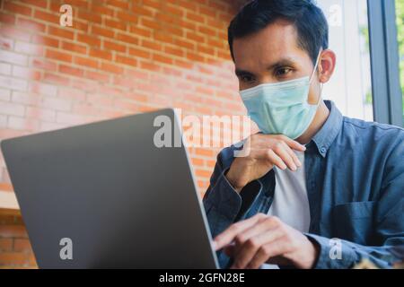 Asian man wear face mask working computer at home, Trading online at home Stock Photo