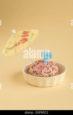 A small birthday cake with heart shaped candle and umbrella on yellow Stock Photo