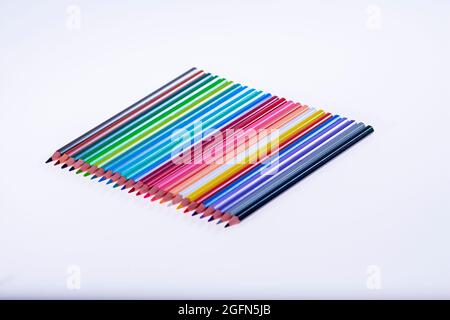 24 multicolored crayons on a white background, neatly arranged and sharpened. Hello School Stock Photo