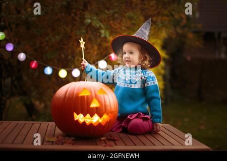 Kids trick or treat in Halloween costume. Children in colorful dress up with candy bucket on suburban street. Little girl trick or treating Stock Photo