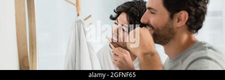 happy gay couple brushing teeth in bathroom, banner Stock Photo