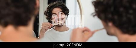 cheerful gay couple brushing teeth in bathroom, banner Stock Photo