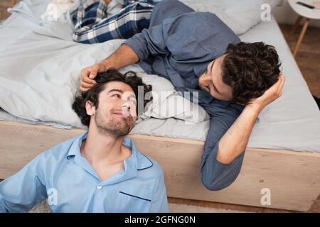 caring man stroking hair of boyfriend in bedroom Stock Photo