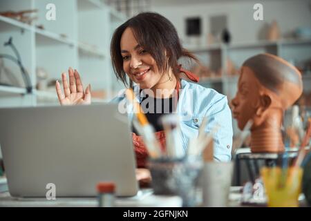 Nice female potter using laptop in pottery workshop Stock Photo