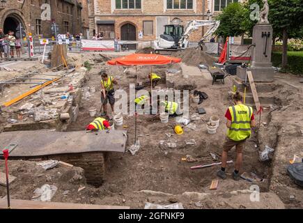 Brugge, Flanders, Belgium - August 4, 2021: Archaeology dig on former cemetery just outside Onze Lieve Vrouw Church walls. People in yellow security v Stock Photo