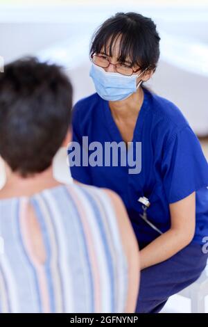 Nurse wearing PPE mask talking to patient Stock Photo