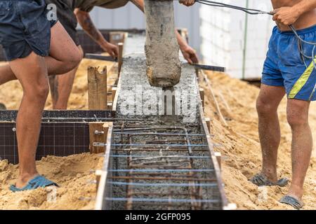 Pouring cement or concrete with automatic pump, construction site with reinforced grillage foundation, start of new house building construction. Stock Photo