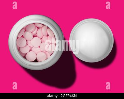 top view of pink pills in white bottle and cap on magenta background Stock Photo