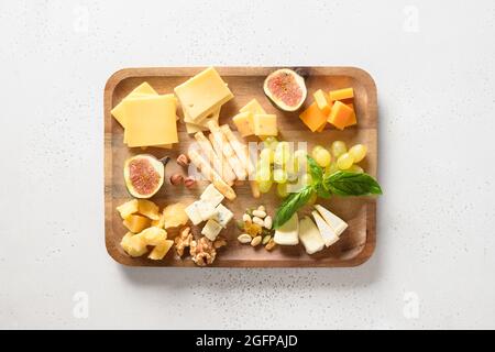 Cheese platter with grapes, nuts, figs on a white background. View from above. Festive gourmet snack. Stock Photo
