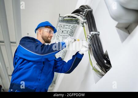 Electrician Doing Cable Installation And Maintenance In Office Stock Photo