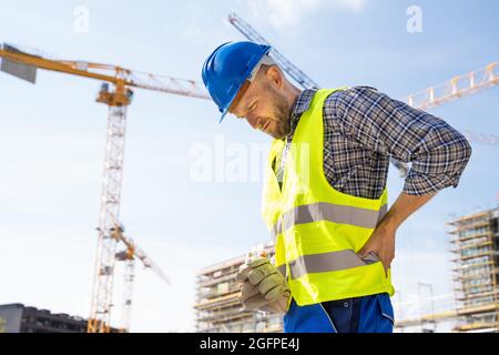Engineer With Back Pain Injury After Accident At Construction Site Stock Photo