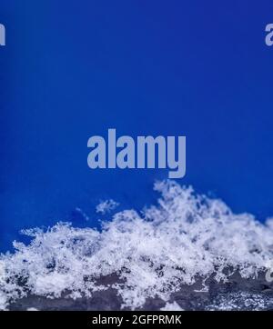 Snow on a large scale. Snowflakes on a blue background. Snow background. Vertical Stock Photo