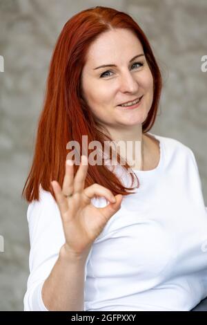 smiling woman with red hair showing her fingers approx. vertical photo portrait, close up Stock Photo