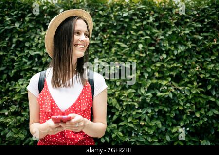 Young hipster woman using smartphone while standing over green background Stock Photo