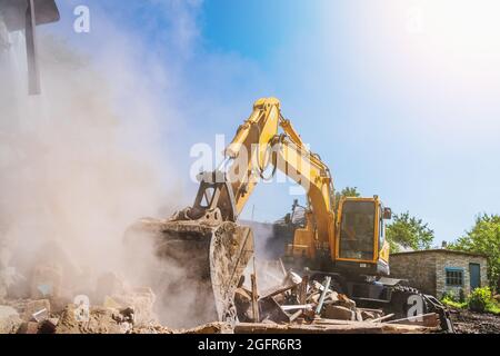 Excavator breaks old house, many dust in air. Building demolition and deconstruction, copy space. Stock Photo