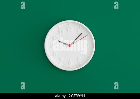 White wall Clock on gree background. Stock Photo