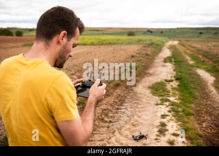 Back View Of An Unrecognizable Caucasian Young Adult Flying A Drone In A Sustainable Windmill Field. Learning Concept. Stock Photo