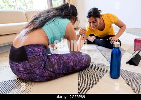Closeup of two girls competing in arm-wrestling at home. Stock Photo