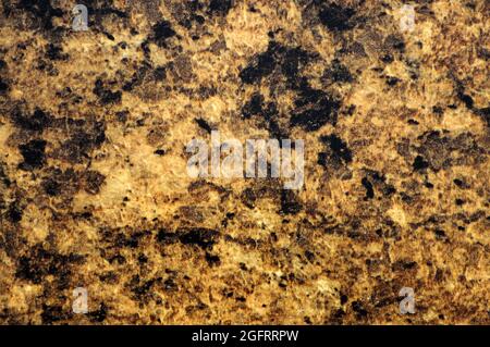 Natural orange granite with small black inclusions, close-up of polished flat stone surface. Background, pattern, texture. Stock Photo