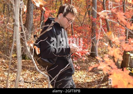 Portrait of Russian young man walking in autumn forest and exploring nature Stock Photo