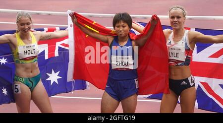 Tokio, Japan. 27th Aug, 2021. Paralympics: Athletics, 100m, women, final, at Olympic Stadium. Silver medallist Isis Holt (l-r) from Australia, gold medallist Xia Zhou from China and bronze medallist Maria Lyle from Great Britain hold national flags in their hands. Credit: Marcus Brandt/dpa/Alamy Live News Stock Photo