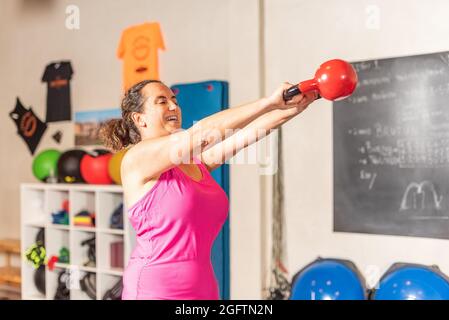 Woman doing kettlebell swing exercise in gym Stock Photo