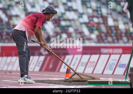 Tokio, Japan. 27th Aug, 2021. Paralympics: Athletics, long jump, at the Olympic Stadium. A volunteer smoothes the sand before the competition. Credit: Marcus Brandt/dpa/Alamy Live News Stock Photo