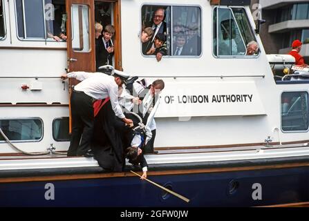 Close up historical 1990s archive view of the old custom & tradition of Beating the Bounds carried out in 1992 by church of All Hallows by the Tower with help from church clergy and boys from St Dunstan’s College school & staff assisted by PLA crew in holding a boy upside down by rope from a 90s Port of London Authority launch to beat the south boundary in river water with a cane an unusual event in the middle of River Thames an archival image in the City of London England UK Stock Photo