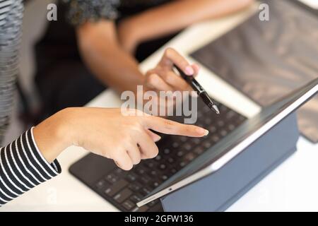 Two business worker brainstorming together, using portable tablet, pointing on screen, top view, close up Stock Photo