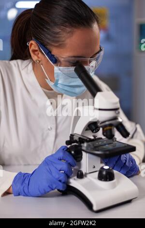 Woman with medical researcher occupation in laboratory working on microscope testing dna sample for development. Professional biochemist worker using medical equipment for treatment innovation Stock Photo