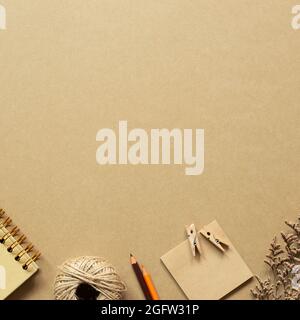 Notebook, twine, colored pencil, notepad, wooden clip, dry flower on brown background. workspace. top view, copy space Stock Photo