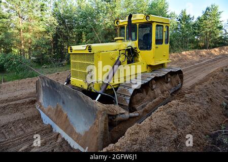 Dozer during clearing forest for construction new road. Bulldozer at forestry work Earth-moving equipment at road work, land clearing, grading, pool e Stock Photo