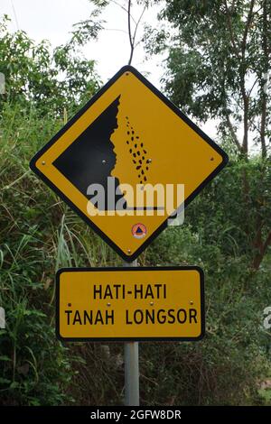 Yellow sign with a natural background. Hati-hati tanah longsor means beware of landslides Stock Photo