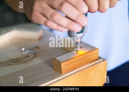 Close up view of a man's hands using an electric screwdriver to Stock Photo