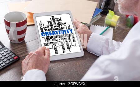 Creativity word cloud concept shown on a tablet held by a man Stock Photo