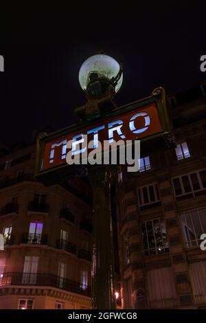 Traditional parisian metro (underground, subway) sign with old, historical building in the background in Paris. Stock Photo