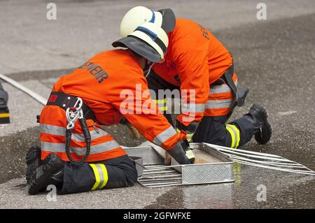firefighter rolling up a fire hose, Germany Stock Photo