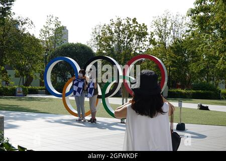 Tokio, Japan. 27th Aug, 2021. Visitors have their picture taken in front of the Olympic rings at the Olympic Stadium. Credit: Marcus Brandt/dpa/Alamy Live News Stock Photo